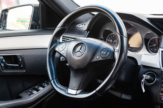 The interior of the car Mercedes Benz E-class E250 with a view of the steering wheel, dashboard, seats and multimedia system with light gray trim