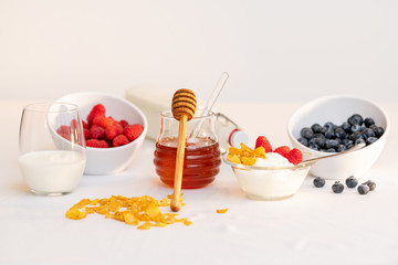 Milk and honey surrounded by cereal and berries