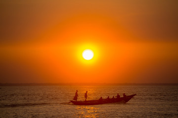 Fototapeta premium Colorful golden Sunset on Sea. Fishermans are returning home with fish, manually at sunset on Char Samarj beach at Chandpur, Bangladesh.