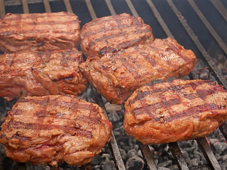 Large pieces of meat are roasted on metal bars