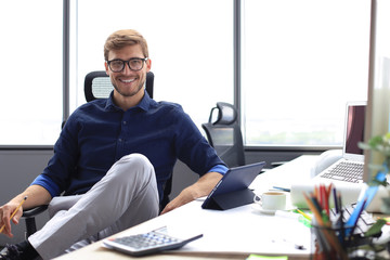 Young modern business man working using digital tablet while sitting in the office.