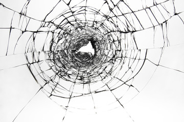 Obraz premium Cracks on broken glass. The window is damaged by a shot from a firearm. Transparent windscreen of a car with a hole after the shots.
