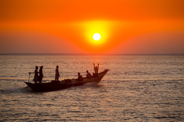 Colorful golden Sunset on Sea. Fishermans are returning home with fish, manually at sunset on Char Samarj beach at Chandpur, Bangladesh.