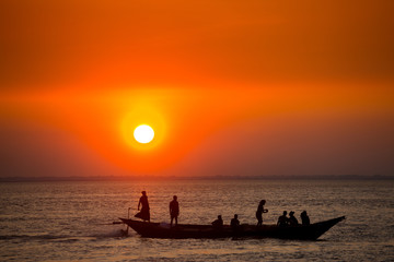 Naklejka na ściany i meble Colorful golden Sunset on Sea. Fishermans are returning home with fish, manually at sunset on Char Samarj beach at Chandpur, Bangladesh.