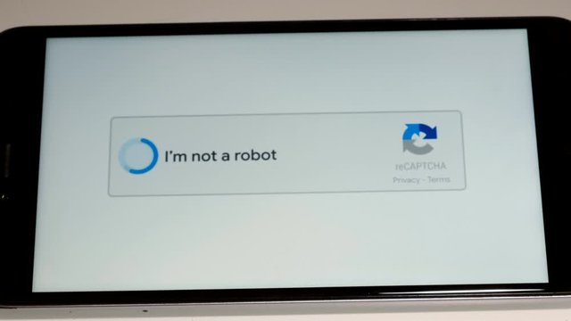 Close-up of a robot hand singing captcha on a smartphone.