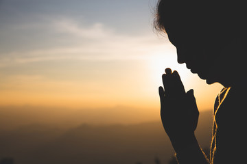 silhouette of a woman  Praying hands with faith in religion and belief in God On the morning...