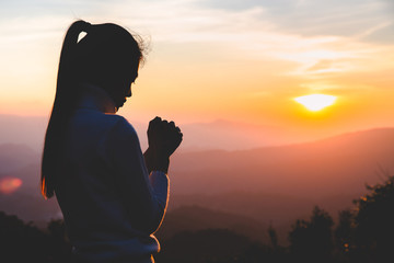 Woman praying in the morning on the sunrise background. Christianity concept. Pray background....