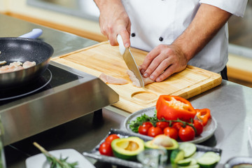 Chef hands cutting chicken, cooking in restaurant kitchen. Close up photo. Professional food concept.