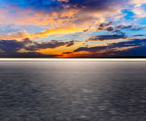 Fototapeta premium Car-free asphalt pavement with sunset sky.