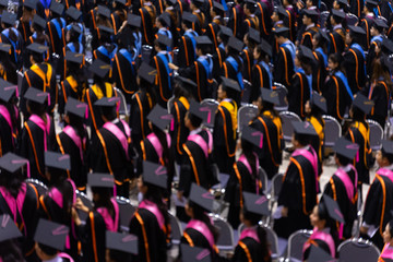 Fototapeta premium Rear view and soft selective focus of the graduates in the graduation commencement ceremony recieving diploma degree certificate.