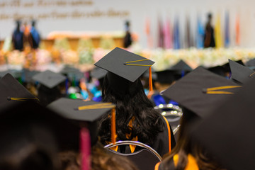 Rear view and soft selective focus of the graduates in the graduation commencement ceremony recieving diploma degree certificate.