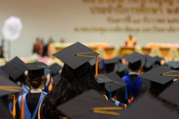 Rear view and soft selective focus of the graduates in the graduation commencement ceremony recieving diploma degree certificate.
