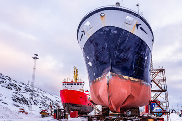 Fishing ships hulls in dockyard on maintenance during the winter time, port of Nuuk, Greenland