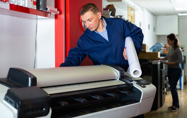 Worker loads new roll of paper into the plotter