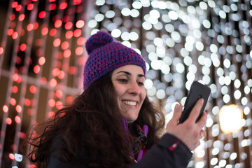 woman with smartphone land christmas lights sending message