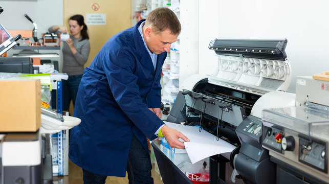 Worker loads new roll of paper into the plotter