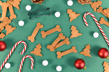Homemade baked dog treat cookies in shape of bones and christmas tree on festive green background...