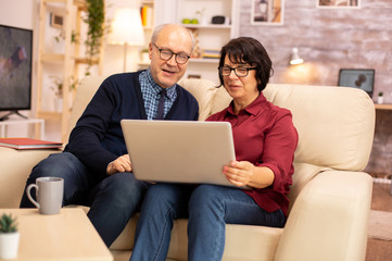 Elderly old couple using modern laptop to chat with their grandson