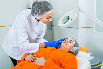 Woman doctor making beauty injection to young female client