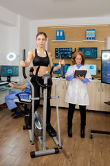 Fit female testing stepper and doctor making notes in tablet