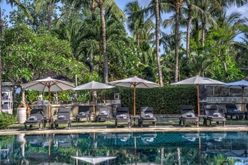 reclining lounge chairs under large umbrellas next to swimming pool