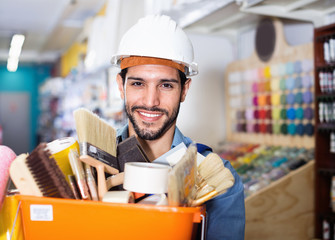 Workman holding basket with picked tools in paint store