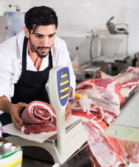 Man butcher is weighing meat in the market.