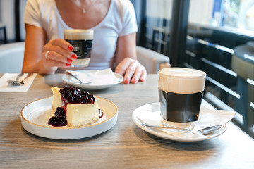 Woman eating cake and drinking coffee at a cafeteria.