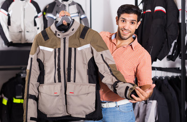 Fototapeta na wymiar Man is demonstrating new jacket for motorbike in the store.