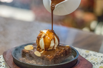 hot chocolate brownie on sizzling hot plate with vanilla ice cream and topped with almond flakes and hot chocolate sauce