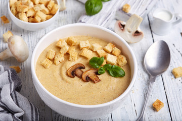 Bowl of champignon mushroom cream soup puree with croutons and basil leaf. Delicious homemade dish. 