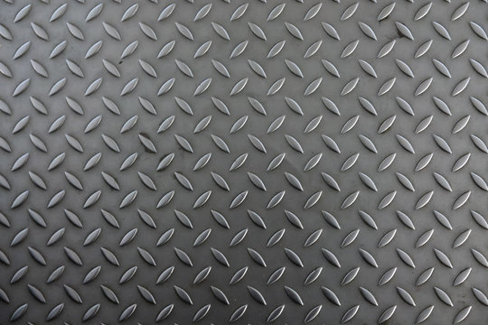Corrugated metal sheet for the floor. The color is silver gray. The structure of the sheet is worn by prolonged use as part of the construction of the pedestrian path. Background. Texture.