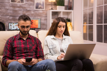 Young couple sitting on sofa and doing online shopping