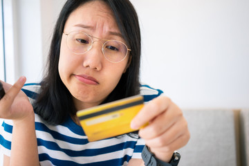 Confused portrait young woman holding credit cards having problem online payment with credit card making rejected unsecure online payment. credit card debt payment