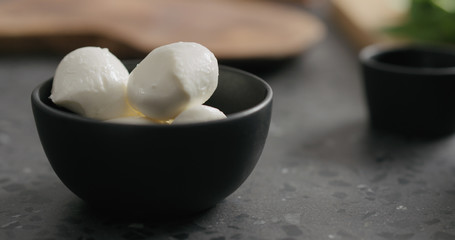 Fototapeta na wymiar small mozzarella balls in black bowl on terrazzo countertop