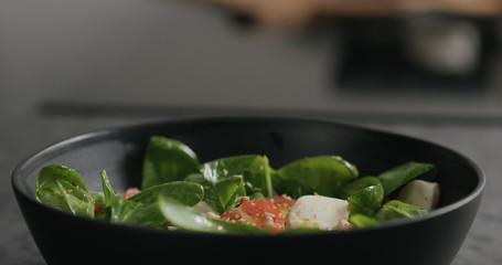 fresh salad with mozzarella, cherry tomatoes and spinach decorated with walnuts