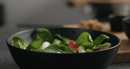 fresh salad with mozzarella, cherry tomatoes and spinach decorated with walnuts