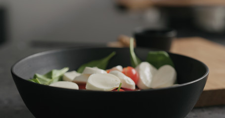 Closeup making salad with spinach, tomatoes and mozzarella
