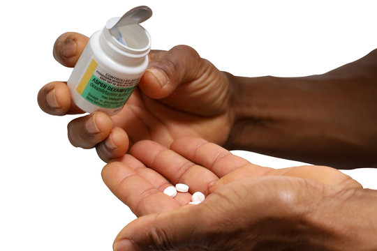 Male patient holding Attention Deficit Hyperactivity Disorder (ADHD) legal drug bottle and counting his tablets in the palm prior taking daily medication treatment with white background     
