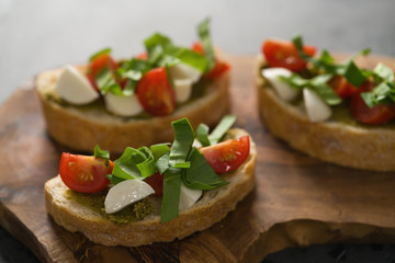 Fototapeta na wymiar Bruschetta with mozzarella, cherry tomatoes and pesto on olive board