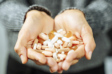 Close up of female hands holding many different pills and capsules