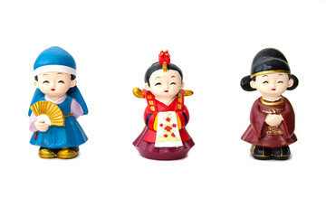 Three decorative ceramic Korean figures, two women and man, standing in line in traditional colorful clothes Han bock. Figures are allocated over a white background. Collecting. Hobby and leisure.