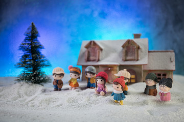 Christmas and New Year holidays concept. Little decorative cute small houses in snow at night in winter, Fir tree standing on snow with beautiful holiday decorated background