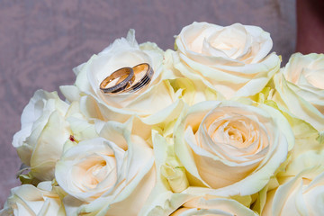 wedding rings on a bouquet of white roses