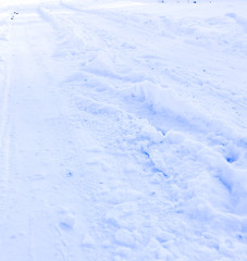 car tires on a winter road covered in snow. car tracks on a snowy alley in the morning with snowfall