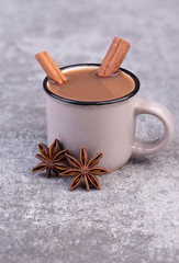 Cup of coffee with star anise and cinnamon on a grey structured background