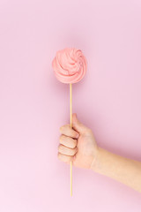 Hand holds marshmallow candy on a pink background