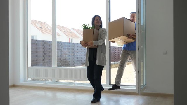 Happy man and woman with cardboard boxes enter in new house, embrace couple