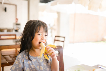 Happy Little girl eating banana.5 years old girl eat banana in restaurant.