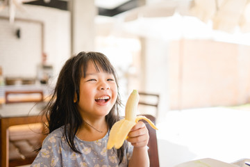 Happy Little girl eating banana.5 years old girl eat banana in restaurant.